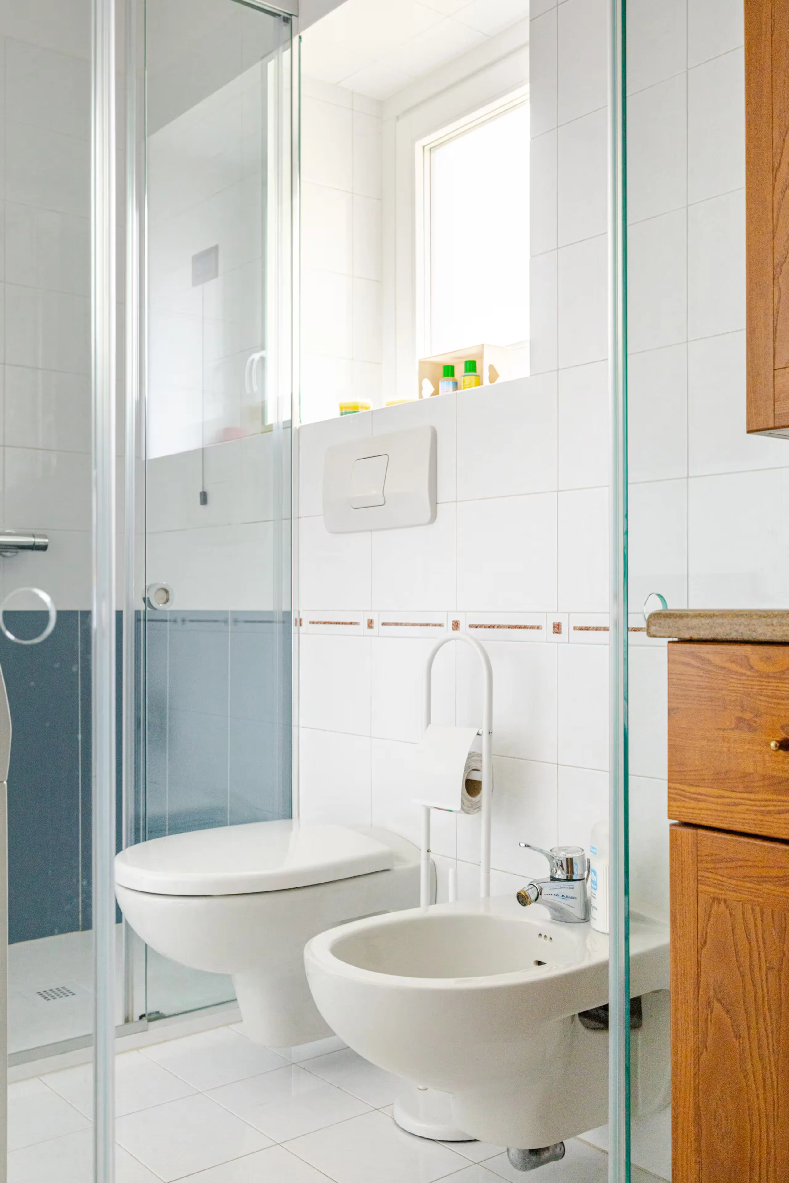 Doccia in vetro, sanitari sospesi e finestra luminosa nel bagno principale