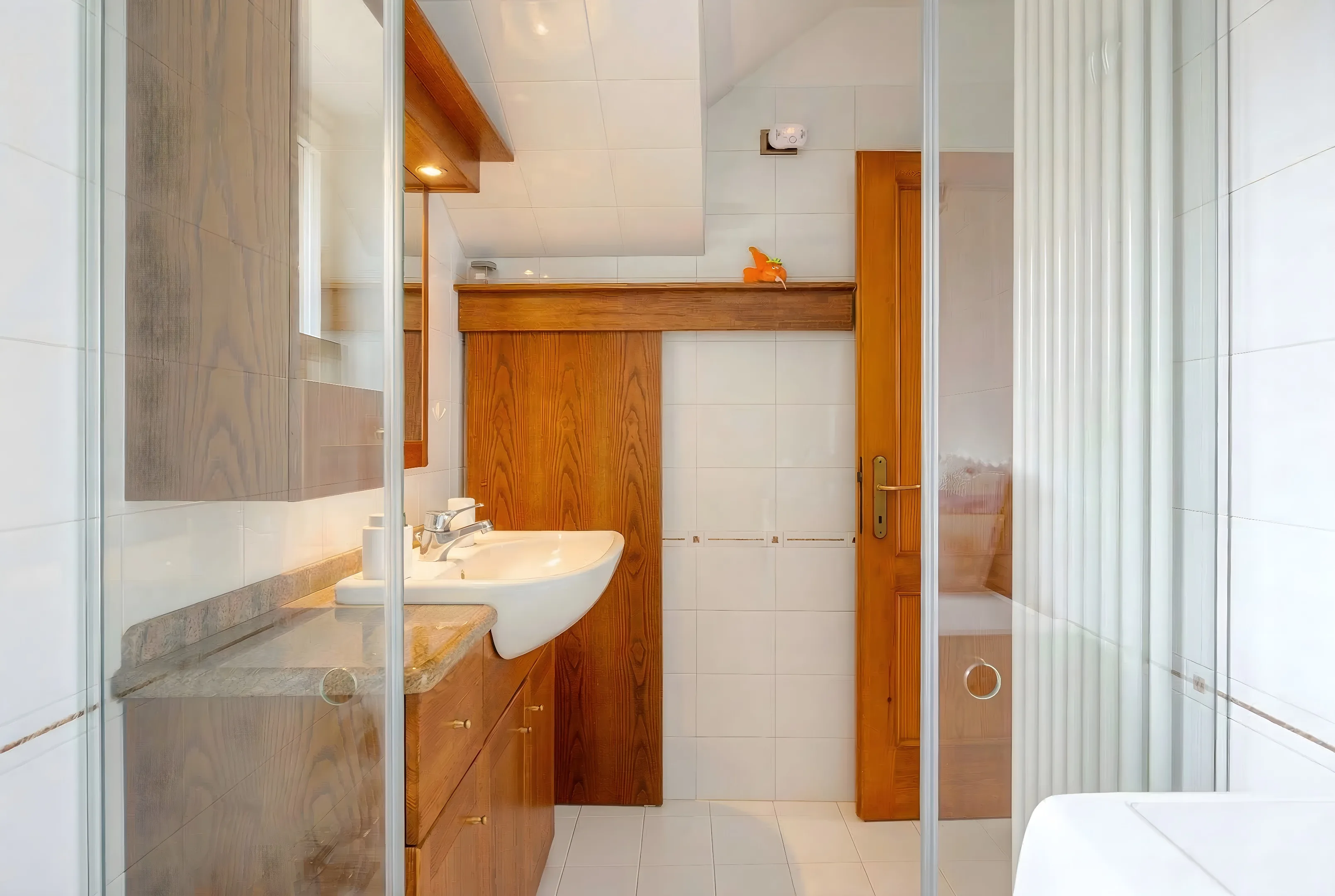 Bagno con lavabo, mobile in legno e cabina doccia in vetro