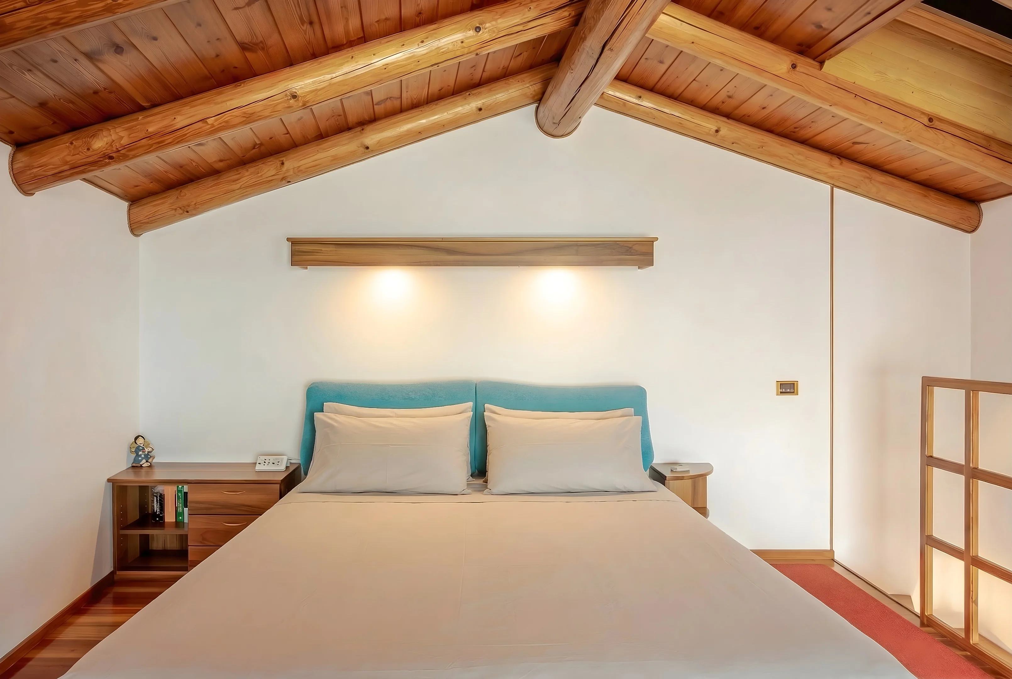 Camera matrimoniale con testiera azzurra e soffitto con travi in legno