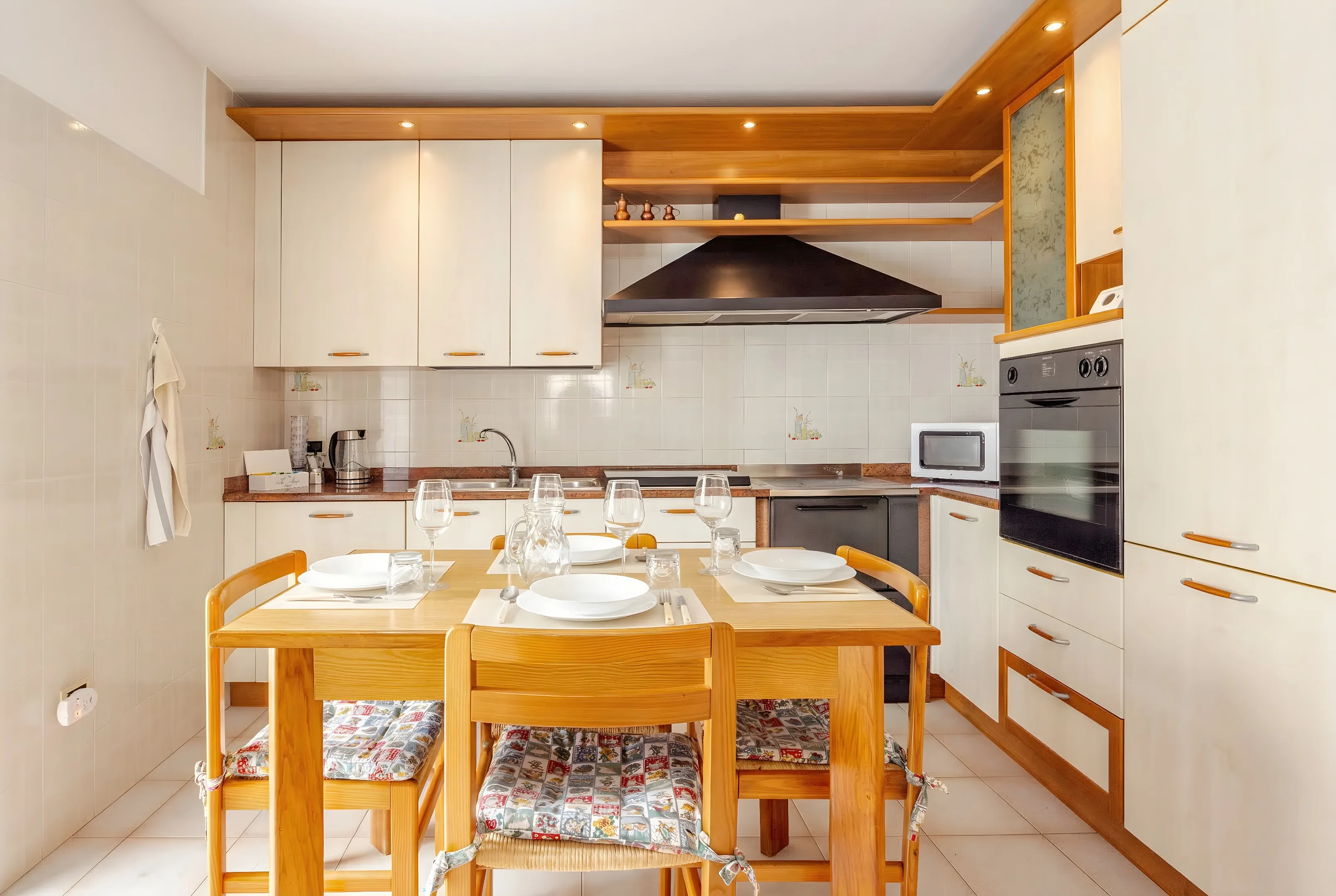 Cucina con pensili chiari e tavolo da pranzo in legno apparecchiato